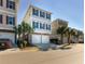 Attractive three-story beach home boasting a two-car garage and lush palm trees at 4904 Salt Creek Ct., North Myrtle Beach, SC 29582