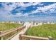 Beach access featuring wooden walkway and native vegetation. The view opens to a wide sandy beach and blue skies at 4933 Crab Pond Ct. # 202, Myrtle Beach, SC 29579