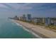 A picturesque coastal view featuring sandy beach, oceanfront hotels, and a clear sky. People are seen enjoying the beach at 4933 Crab Pond Ct. # 202, Myrtle Beach, SC 29579