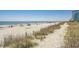 A serene beach view highlighting the sandy shore, gentle waves, and a clear sky. People can be seen enjoying the beach at 4933 Crab Pond Ct. # 202, Myrtle Beach, SC 29579