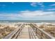 A wooden walkway leads to a picturesque beach with ocean views and calming waves at 6644 E Sweetbriar Trail, Myrtle Beach, SC 29588