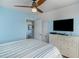 This cozy bedroom includes a television, coastal artwork, and a ceiling fan at 719 N Waccamaw Dr., Garden City Beach, SC 29576