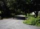 An open electric entrance gate leads to a gravel drive and landscaped yard, ensuring privacy at 76 Nailah Ln., Pawleys Island, SC 29585