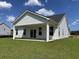 Rear exterior view of white siding home, showcasing a covered patio and well-manicured lawn at 148 Joyce Dr, Longs, SC 29568