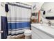 Cozy bathroom with stylish decor, white vanity, decorative ladder, and striped shower curtain at 1510 S Ocean Blvd. # 101, Surfside Beach, SC 29575