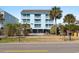 Bright, three-story beach condo with multiple balconies, palm trees, and a black metal fence at 1510 S Ocean Blvd. # 101, Surfside Beach, SC 29575