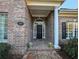 Inviting front entrance with a classic black door, white columns, brickwork, and a decorative wreath at 165 Greenbriar Ave., Pawleys Island, SC 29585