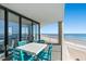 Oceanfront balcony with a table and chairs offering scenic views of the beach at 1990 N Waccamaw Dr. # 401, Murrells Inlet, SC 29576