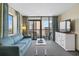 Bright living room with a blue sofa, TV, and sliding glass doors leading to an outdoor balcony at 2301 S Ocean Blvd. # 825, Myrtle Beach, SC 29577