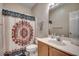 Well-lit bathroom with a wooden vanity and a decorative shower curtain over the tub at 4225 Rivergate Ln., Little River, SC 29566