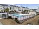 Community pool area surrounded by black fencing, tropical foliage, and parking at 805 Sunswept Ct. # 102, Murrells Inlet, SC 29576