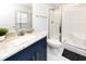 Bright bathroom features white tile floors, blue vanity with granite top, toilet, and a walk-in shower at 114-B 7Th Ave. N, Surfside Beach, SC 29575