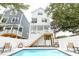 Bright shot of backyard pool with white vinyl privacy fence, lounge chairs and elevated home with stair access at 114-B 7Th Ave. N, Surfside Beach, SC 29575