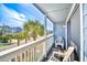 Balcony view of the street with chairs and a white railing with palm trees at 1210 N Ocean Blvd. # 202, Surfside Beach, SC 29575