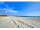 Expansive sandy beach with tire tracks leading towards the ocean under a blue sky at 1210 N Ocean Blvd. # 202, Surfside Beach, SC 29575