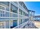 Multi-story condo building featuring blue siding, white railings, and exterior staircases at 1210 N Ocean Blvd. # 202, Surfside Beach, SC 29575
