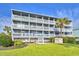 Four-story condo building with white railings and palm trees on a sunny day at 1210 N Ocean Blvd. # 202, Surfside Beach, SC 29575