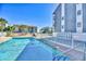 Community pool area with clear blue water, views of building, and ample seating for residents at 1210 N Ocean Blvd. # 202, Surfside Beach, SC 29575