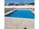 A bright blue rectangular in-ground pool is surrounded by brick pavers with a white fence in the background at 153 Highmeadow Ln., Aynor, SC 29511