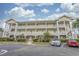 Three-story condominium building with white balconies, brick facade and manicured landscaping offering a welcoming appeal at 4179 Hibiscus Dr. # 303, Little River, SC 29566