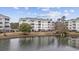 Exterior view of building overlooking a pond, with well maintained landscaping at 4865 Luster Leaf Circle # 304, Myrtle Beach, SC 29577