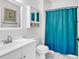 Bright bathroom with a white vanity, toilet, cabinet, mirror and blue shower curtain at 5750 Oyster Catcher Dr. # 533, North Myrtle Beach, SC 29582