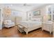 Cozy bedroom featuring wood floors, a ceiling fan, large windows with shutters, and a queen size bed at 6514 Anchors Bend Dr Sw, Ocean Isle Beach, NC 28469