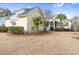 Side view of a charming yellow home with mature palm trees and manicured lawn at 6514 Anchors Bend Dr Sw, Ocean Isle Beach, NC 28469