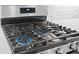 Close-up of gas cooktop with stainless steel trim, digital display, and white subway tile backsplash at 6514 Anchors Bend Dr Sw, Ocean Isle Beach, NC 28469