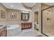 Bathroom with a walk-in shower, soaking tub, double vanity sinks, and neutral tile at 9547 Edgerton Dr. # Ph1005, Myrtle Beach, SC 29572