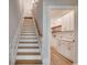 Elegant staircase with wood steps and white railing, leading to a laundry area with white cabinetry and modern design at 1007 Brood Ct., Conway, SC 29526