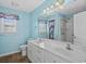 A blue bathroom features a double vanity sink, toilet, walk-in shower, and window with blinds at 1021 Dunraven Ct., Conway, SC 29527