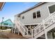 Two-story home with gray siding, white stairs leading up to the entrance, and a view of a nearby blue house at 1031 N Dogwood Dr., Surfside Beach, SC 29575