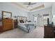 Light-filled bedroom with a tray ceiling, ceiling fan, and a bed with a rustic headboard and blue accents at 109 Jessica Lakes Dr., Conway, SC 29526