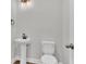 The half bath features a pedestal sink, elongated toilet, wood-look floors, and stylish lighting at 1091 Forest Bend Dr., Calabash, NC 28467