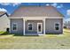 Back of the home featuring grey siding, a covered porch, and a grassy yard under a bright sky at 1111 Forest Bend Dr., Calabash, NC 28467