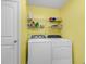 Bright laundry room with yellow walls, washer, dryer, and storage shelves at 1166 Bethpage Dr., Myrtle Beach, SC 29579