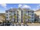 Exterior shot of building with parking lot and beautiful tropical landscaping, blue skies, and covered stairwells at 117 Ella Kinley Circle # 302, Myrtle Beach, SC 29588