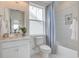 Bright bathroom with a window above the toilet, a sink, and a tiled shower/tub with a blue curtain at 1801 Tryon Dr, Myrtle Beach, SC 29588