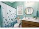 Bright bathroom with teal walls, decorative leaf shower curtain, and a stylish round mirror over the vanity at 250 Ole Maple St., Loris, SC 29569