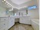 Bright bathroom featuring double sinks, a large mirror with Hollywood lights, and a marble-trimmed tub at 270 Georgetown Dr., Pawleys Island, SC 29585