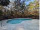 A backyard kidney shaped pool is surrounded by brick and a privacy fence and beautiful trees at 270 Georgetown Dr., Pawleys Island, SC 29585