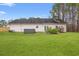 Backyard view of house with hot tub, mature trees, and green lawn at 3471 Spivey St., Loris, SC 29569