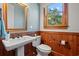 Classic bathroom with wooden accents and a white pedestal sink beneath a large window offering a view of a green tree at 3567 Marion Ln., Murrells Inlet, SC 29576