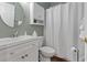 Well-lit bathroom with white vanity, a round mirror, and a shower with a white shower curtain at 5070 Windsor Green Way # 204, Myrtle Beach, SC 29579