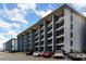 Multi-story condo building with blue siding, featuring private balconies and ample parking at 5905 S Kings Hwy. # 235B, Myrtle Beach, SC 29575