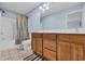 Well-lit bathroom showcasing tile floors, wooden cabinets and a shower with neutral-toned curtain at 624-B Seabreeze Dr., Garden City Beach, SC 29576