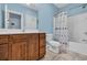 Bright bathroom featuring a wooden vanity, toilet, and a shower/tub with a decorative blue shower curtain at 624-B Seabreeze Dr., Garden City Beach, SC 29576