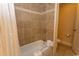 Bathroom featuring a shower-tub combo with tiled walls, and a toilet behind an extended partition wall at 8121 Amalfi Pl. # 4-702, Myrtle Beach, SC 29572