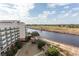 An exterior view features a large building, river and golf course under a bright sky with puffy clouds at 8121 Amalfi Pl. # 4-702, Myrtle Beach, SC 29572